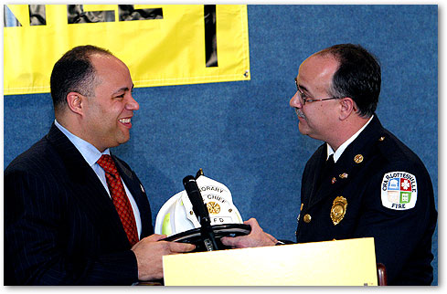 Chairman Powell Accepting Firefighter Hat from Charles Werner, Deputy Chief of the Charlottesville, VA Fire Department.